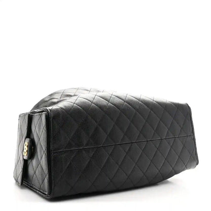 Black quilted leather shoulder bag with top zipper and gold-tone corner tag