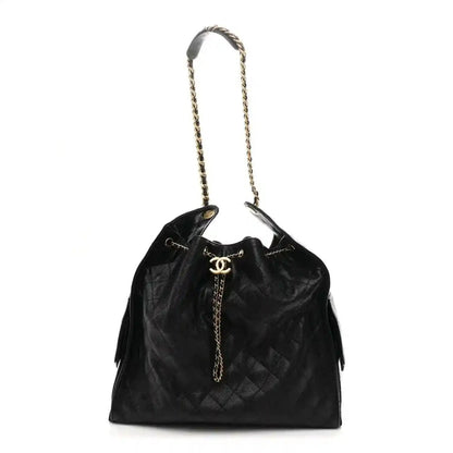 Black quilted leather handbag with chain handles, CC logo, and tassel accents