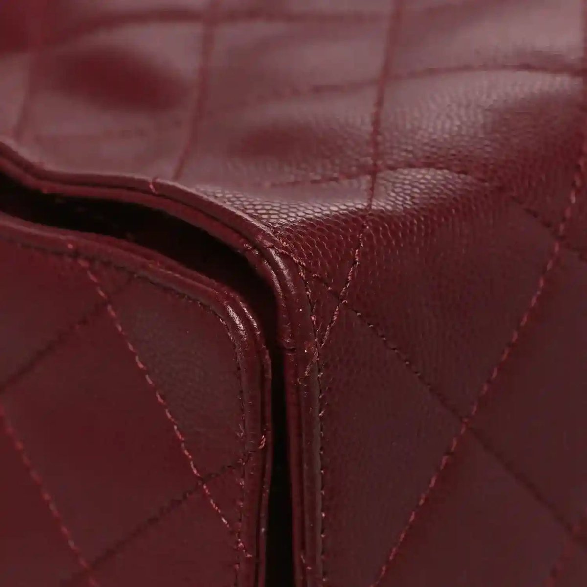 Burgundy quilted leather bag corner with curved piping and stitching