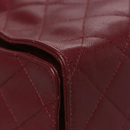 Burgundy quilted leather bag corner with curved piping and stitching
