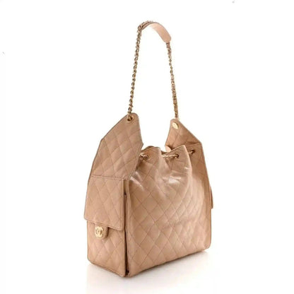 Beige quilted leather handbag side view with top handles and front flap pocket
