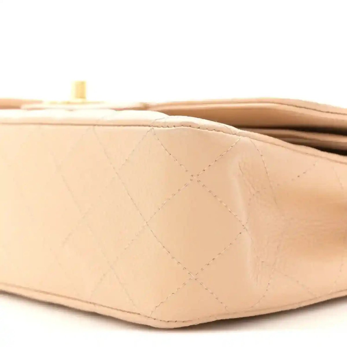 Beige quilted leather bag corner with diamond stitching and top edge hardware