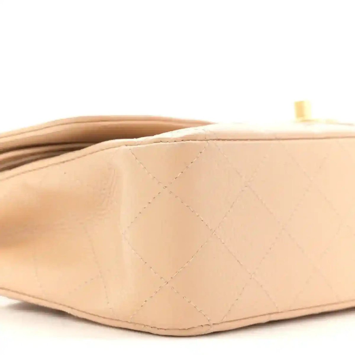 Beige quilted leather bag side with diamond pattern and gold hardware detail at top