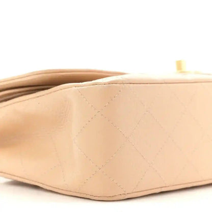 Beige quilted leather bag side with diamond pattern and gold hardware detail at top