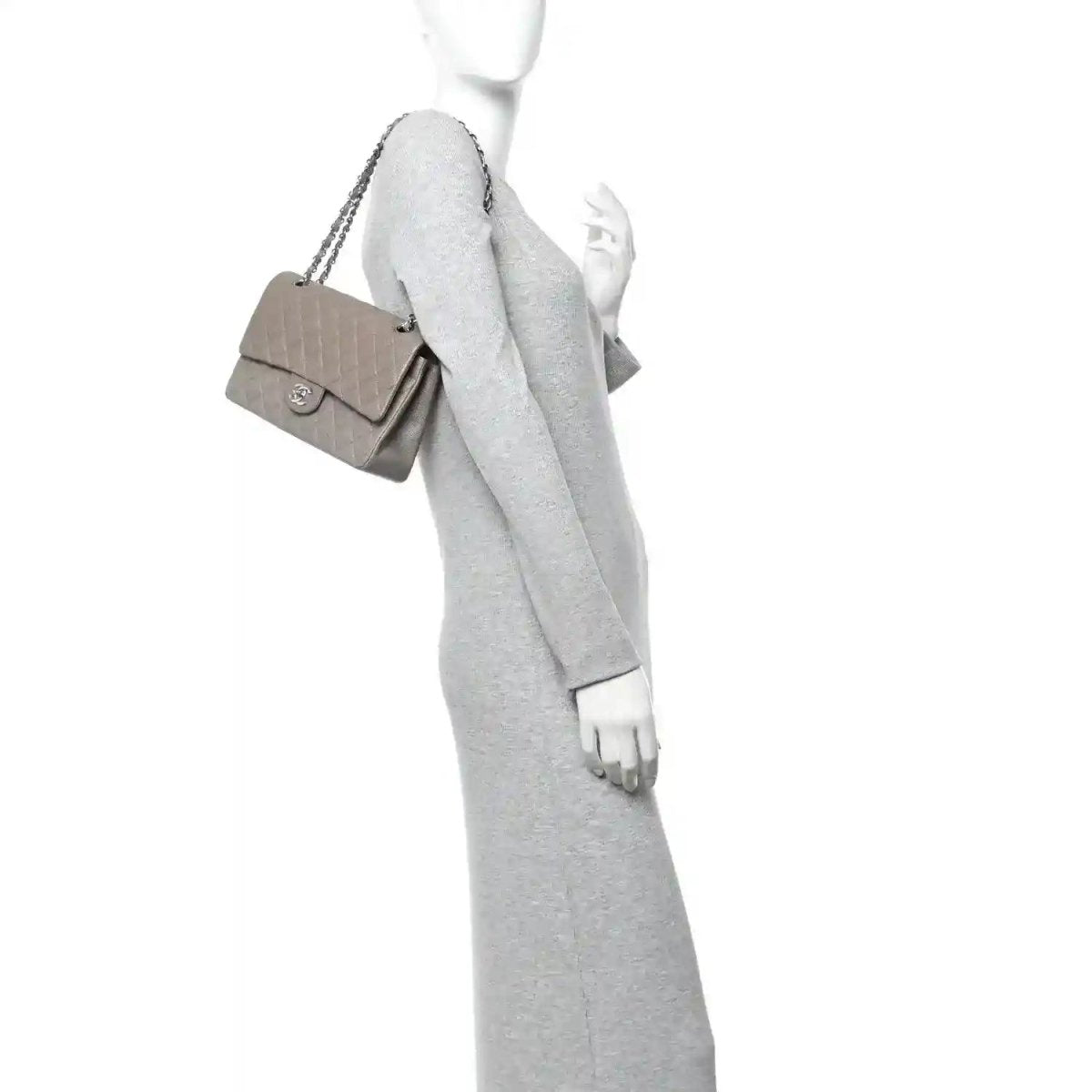 Woman wearing taupe quilted flap bag with short handle and silver chain strap