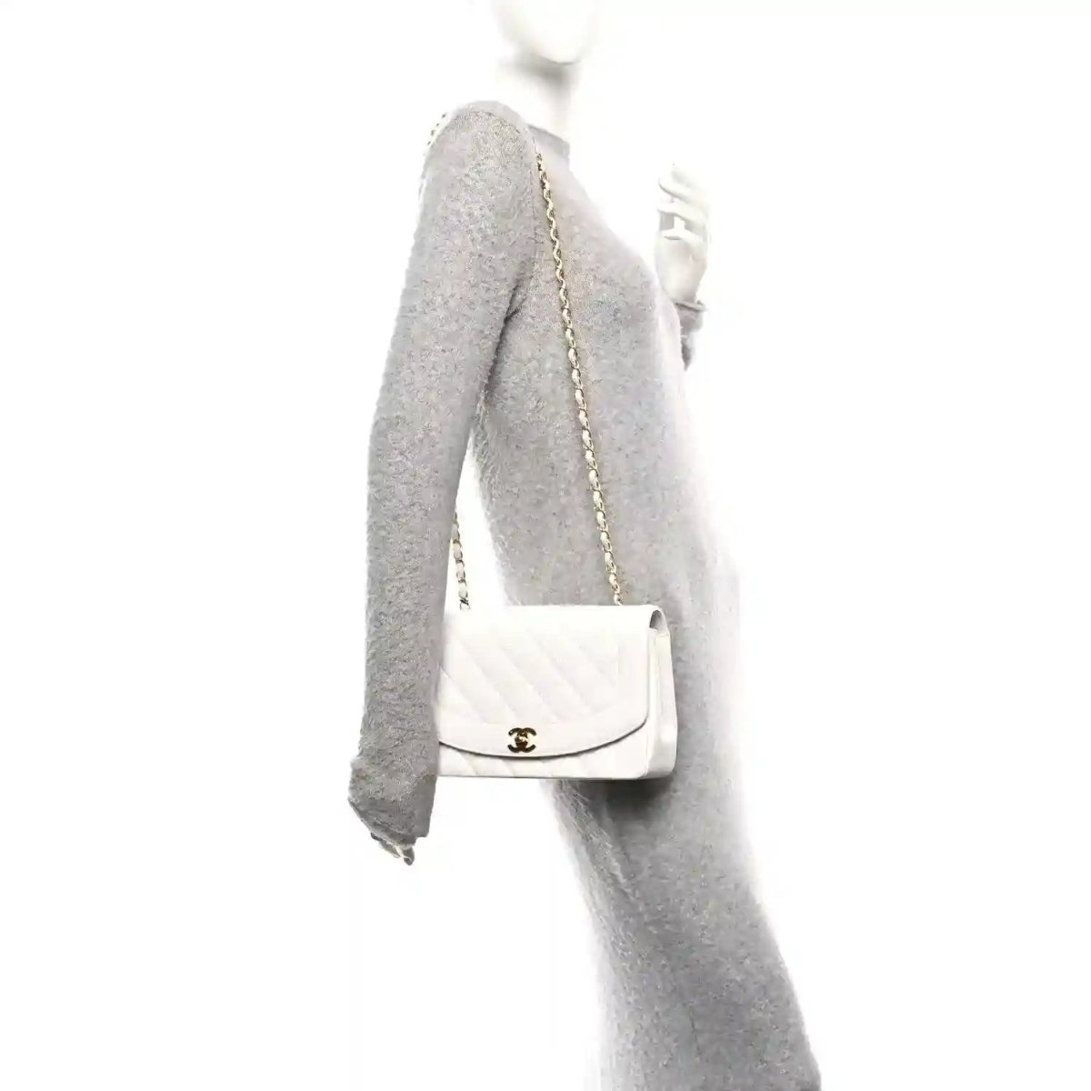 White single-flap bag with gold chain strap, worn over a gray sleeve