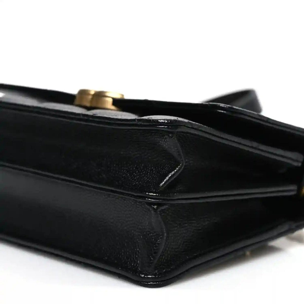 Black quilted mini wallet with flap and chain strap, leather corner close-up
