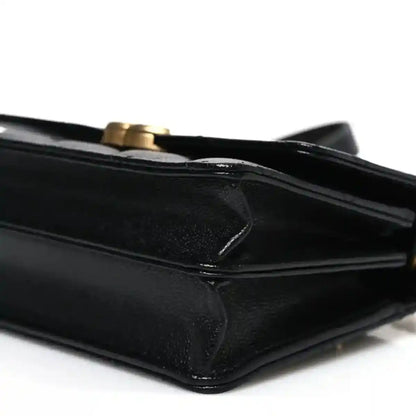 Black quilted mini wallet with flap and chain strap, leather corner close-up