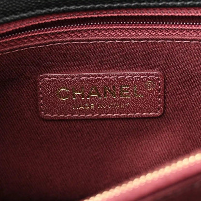 Burgundy interior label inside flap bag with gold Chanel logo text on fabric patch.