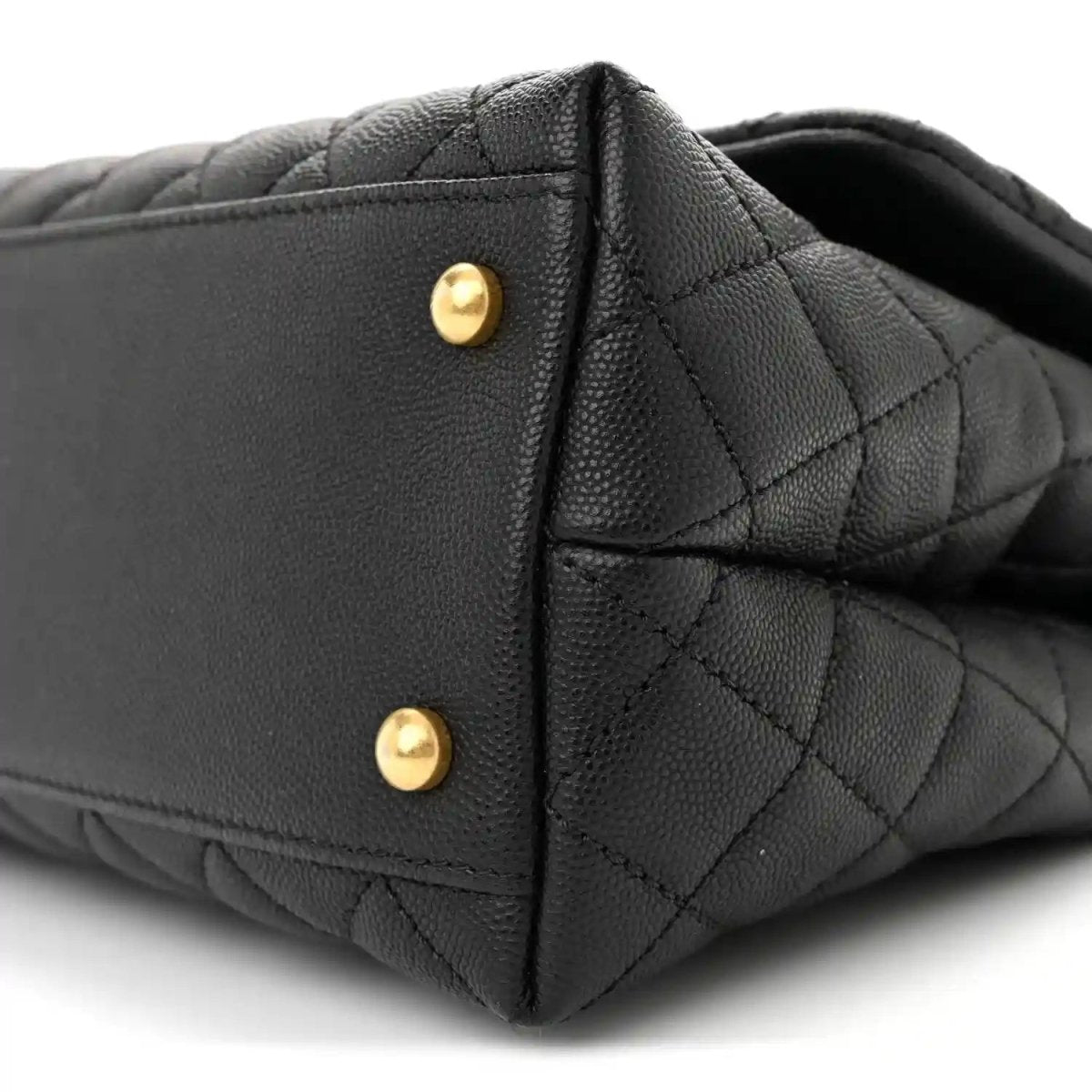 Black quilted flap bag side with gold snap hardware and stitched edge detail.