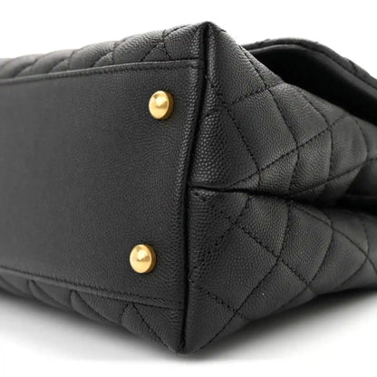 Black quilted flap bag side with gold snap hardware and stitched edge detail.