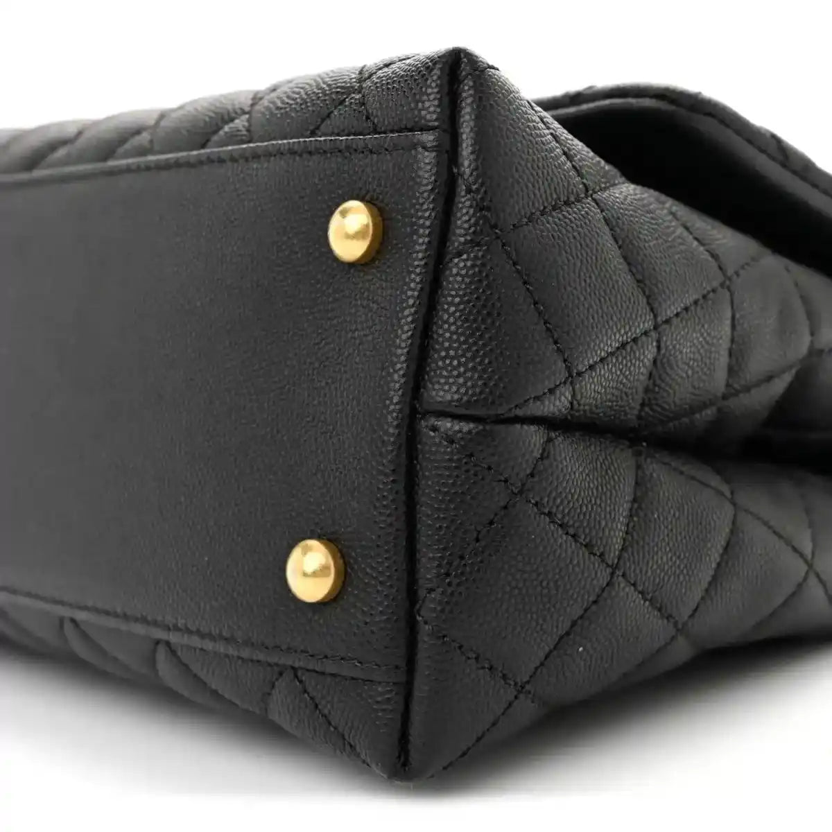 Black quilted flap bag side with gold snap hardware and stitched edge detail.