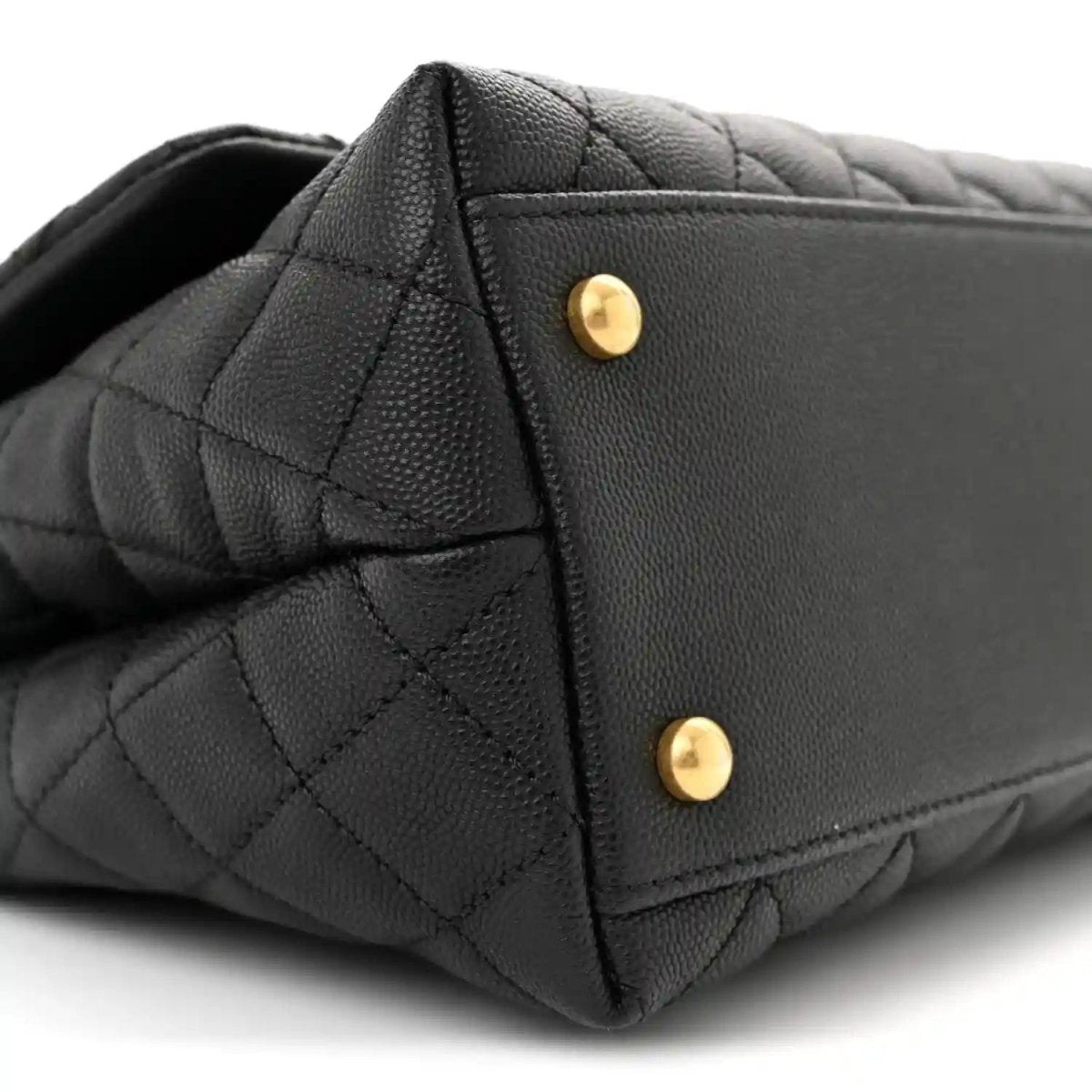 Black quilted flap bag corner with two gold snap buttons on the back panel.