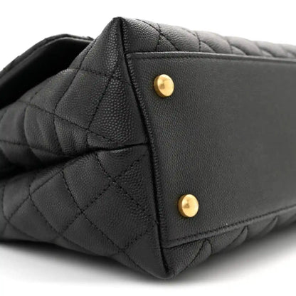 Black quilted flap bag corner with two gold snap buttons on the back panel.