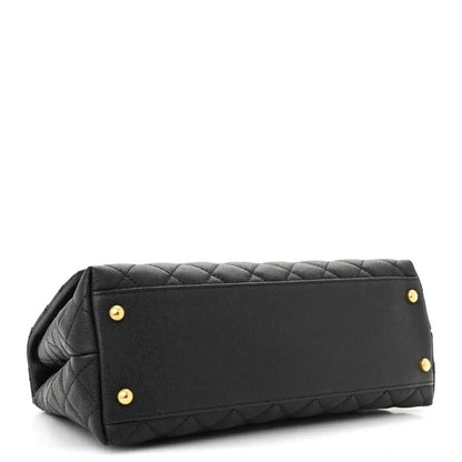 Black quilted small flap bag back panel with gold studs and top handle.
