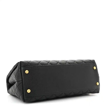 Black quilted small flap bag back panel with gold studs and top handle.