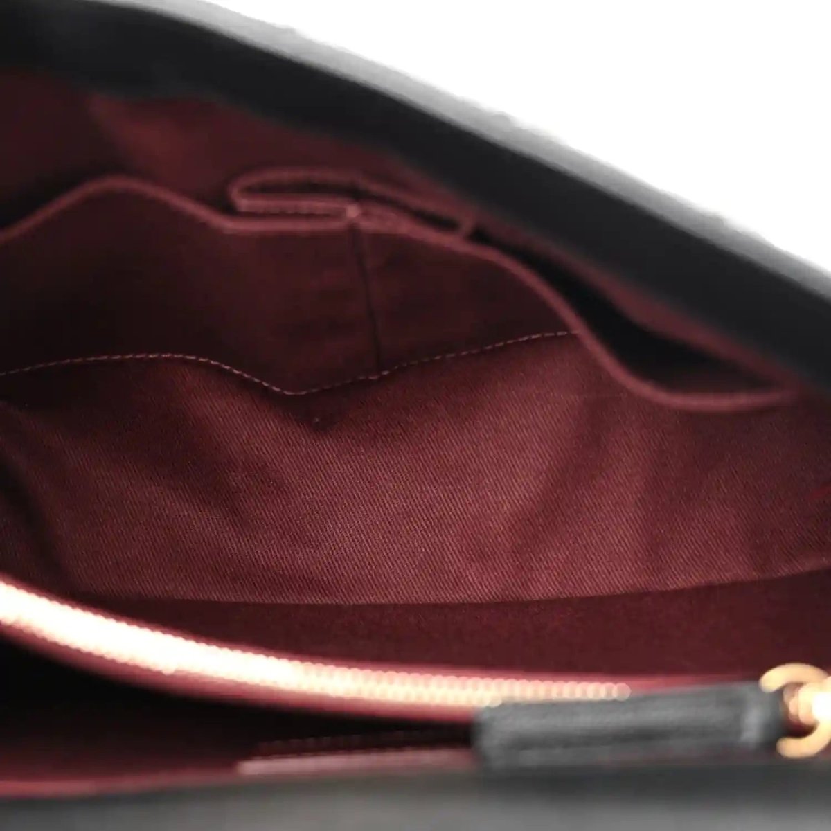 Burgundy fabric lining inside flap bag with stitched edges near the bottom.