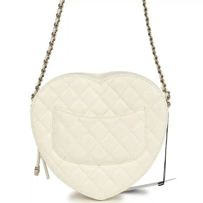 White quilted heart-shaped shoulder bag with flap seam details and chain strap, gold hardware