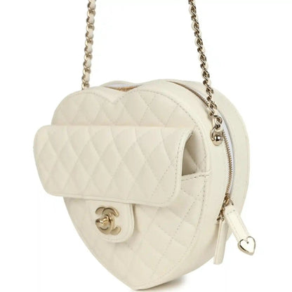 White quilted heart bag with flap open, gold-tone CC clasp, chain strap, and heart pull tab