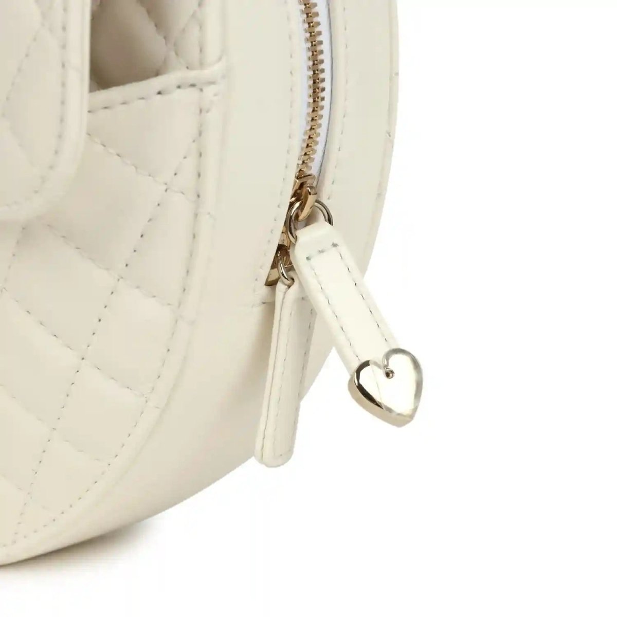 White quilted heart bag close-up of top zipper and heart-shaped charm on gold hardware
