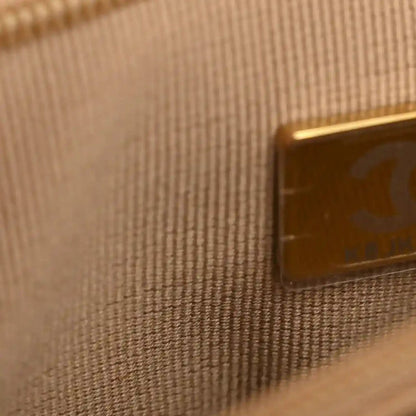 Gold-toned hardware corner on braided raffia nano bag