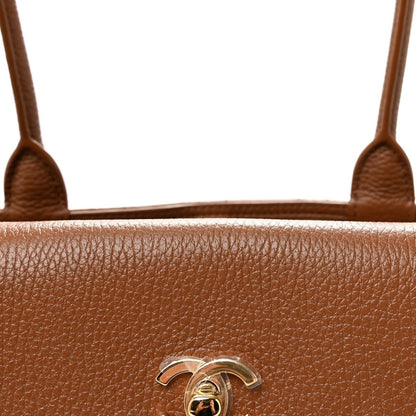 Camel brown grained leather front with metal CC logo detail centered on bag.