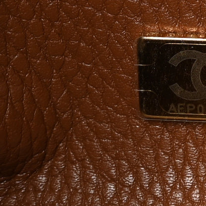 Camel brown leather close-up with embossed stitching and an attached label patch.