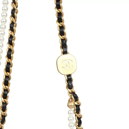 Gold and black chain strap detail with round Chanel CC medallion and pearl beads