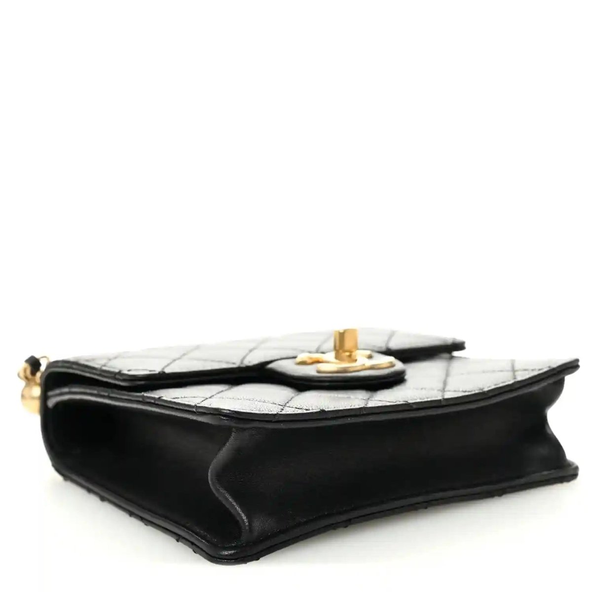 Chanel black quilted flap bag side view with gold-tone turn-lock at the top