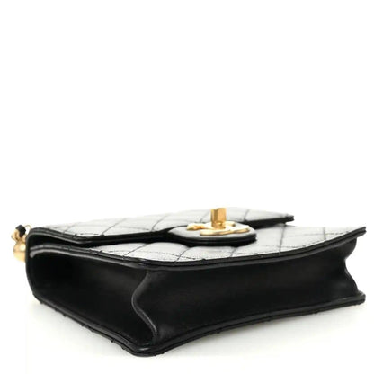 Chanel black quilted flap bag side view with gold-tone turn-lock at the top