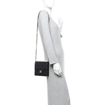 Chanel black quilted flap crossbody bag worn on a model with gold-tone chain strap