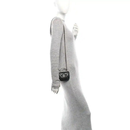 Small black quilted leather clutch with chain strap, shown worn