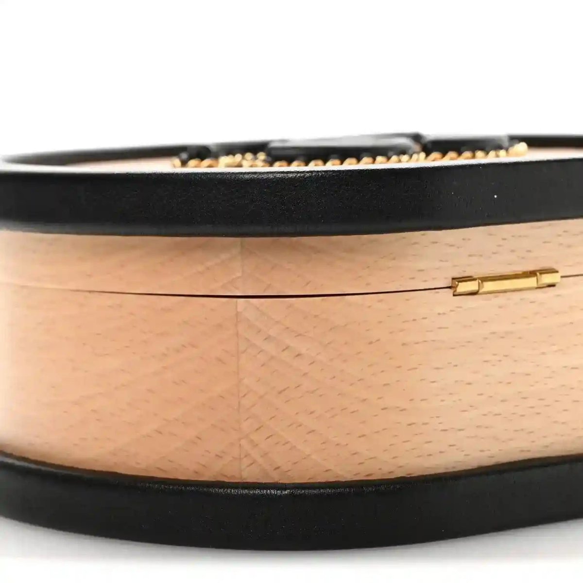 Chanel vanity case side profile with black base trim and gold clasp on light wood