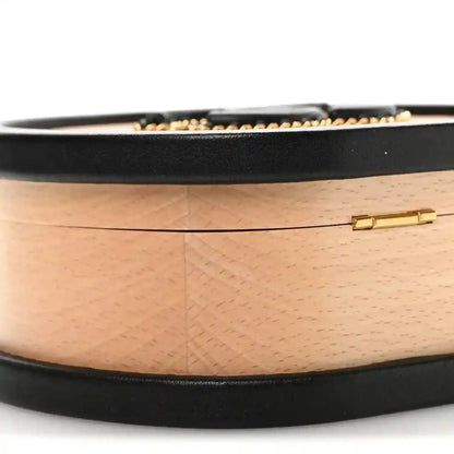 Chanel vanity case side profile with black base trim and gold clasp on light wood