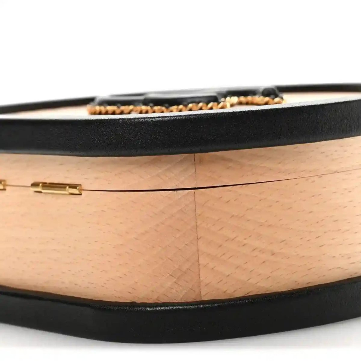 Chanel vanity case top edge with black band and gold hardware on light wood