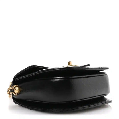 Black leather moon messenger bag side view with gold-tone clasp hardware