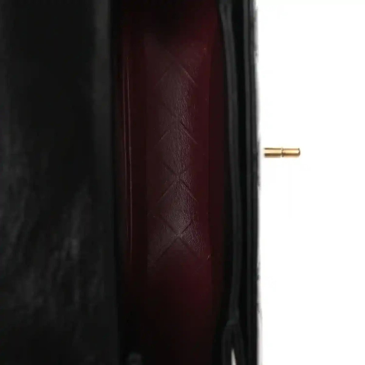 Red leather-lined interior of a black quilted mini messenger bag