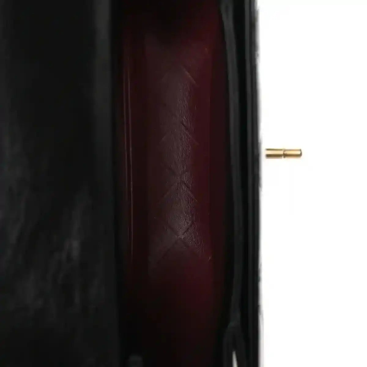 Red leather-lined interior of a black quilted mini messenger bag