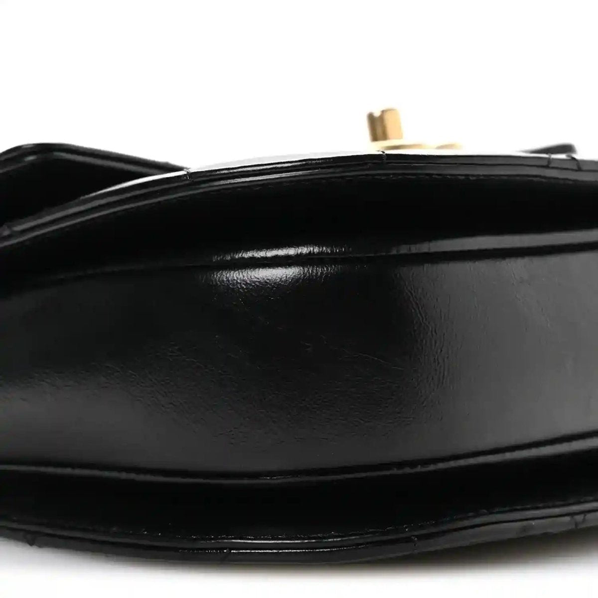 Black leather flap closure detail with gold-tone post and smooth trim