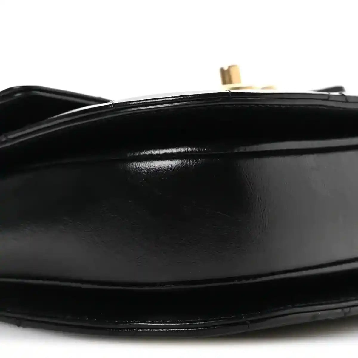 Black leather flap closure detail with gold-tone post and smooth trim