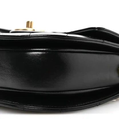 Black leather bag bottom edge with stitching and gold-tone post on top