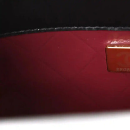 Red leather lining with rectangular authenticity label on black bag interior