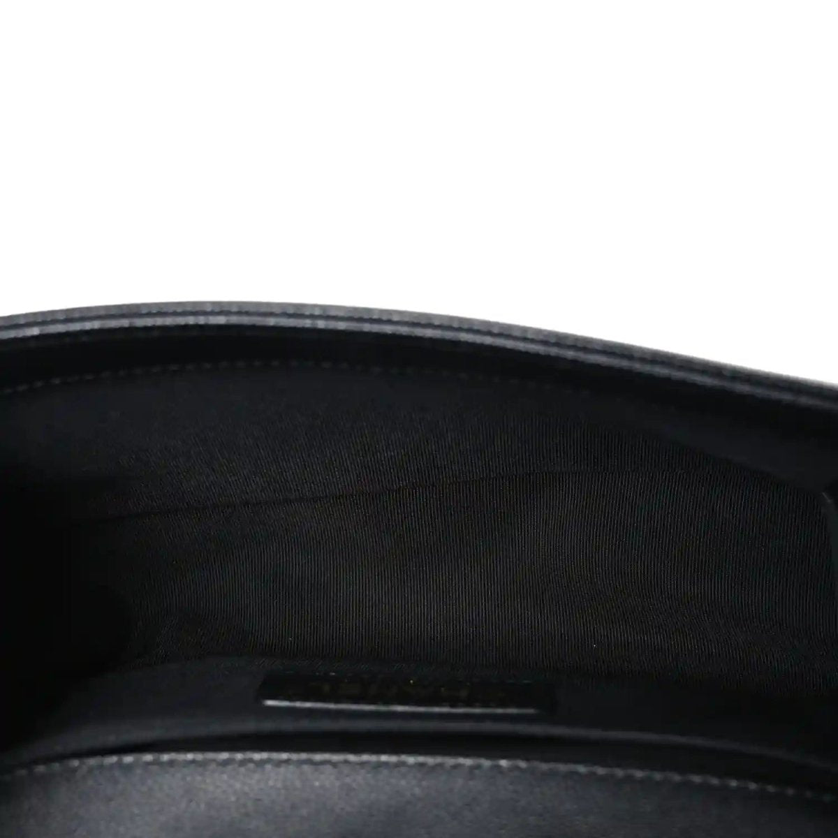 Black fabric-lined interior of a quilted flap bag with zipper pocket visible