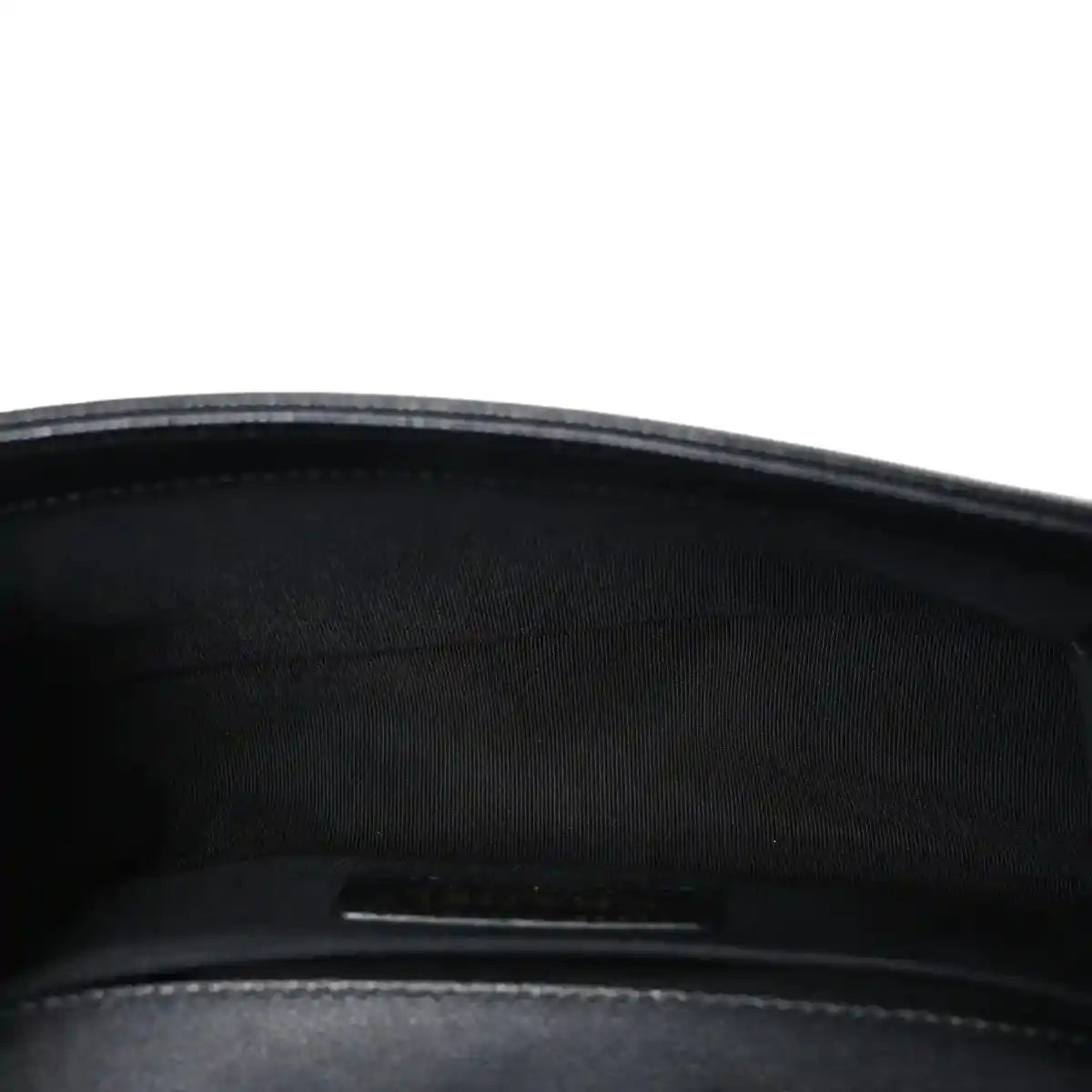 Black fabric-lined interior of a quilted flap bag with zipper pocket visible