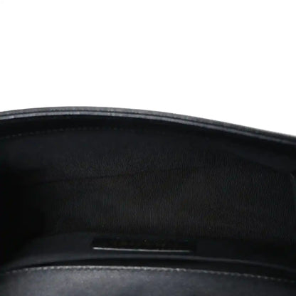 Black fabric-lined interior of a quilted flap bag with zipper pocket visible