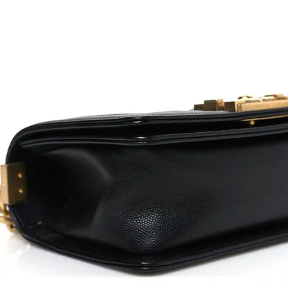 Black leather flap bag corner with gold hardware and smooth exterior texture