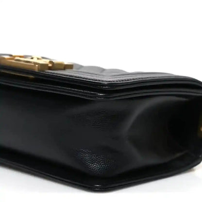 Black leather flap bag side with textured grain and stacked edge stitching