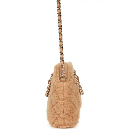 Beige shearling mini crossbody bag with gold chain strap and top handle tab