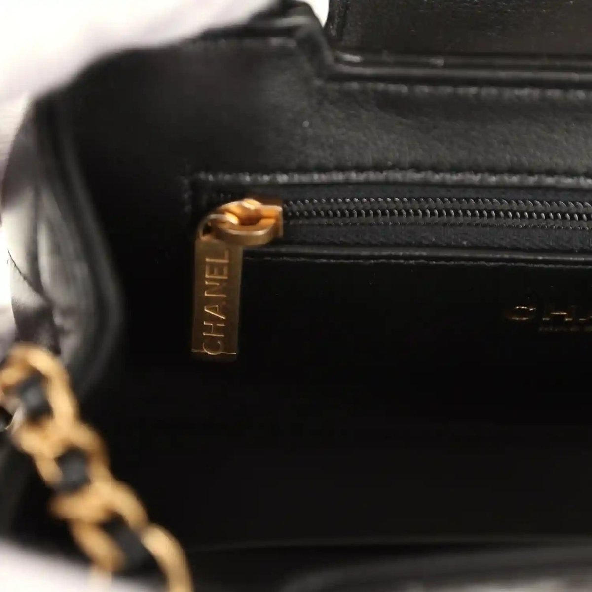 Chanel Kelly shopper bag close-up of black zipper pull with gold logo hardware