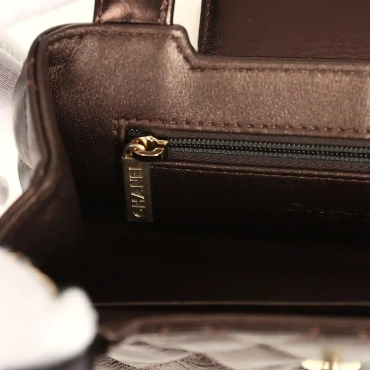Small bag interior pocket with gold zipper pull and textured brown leather trim